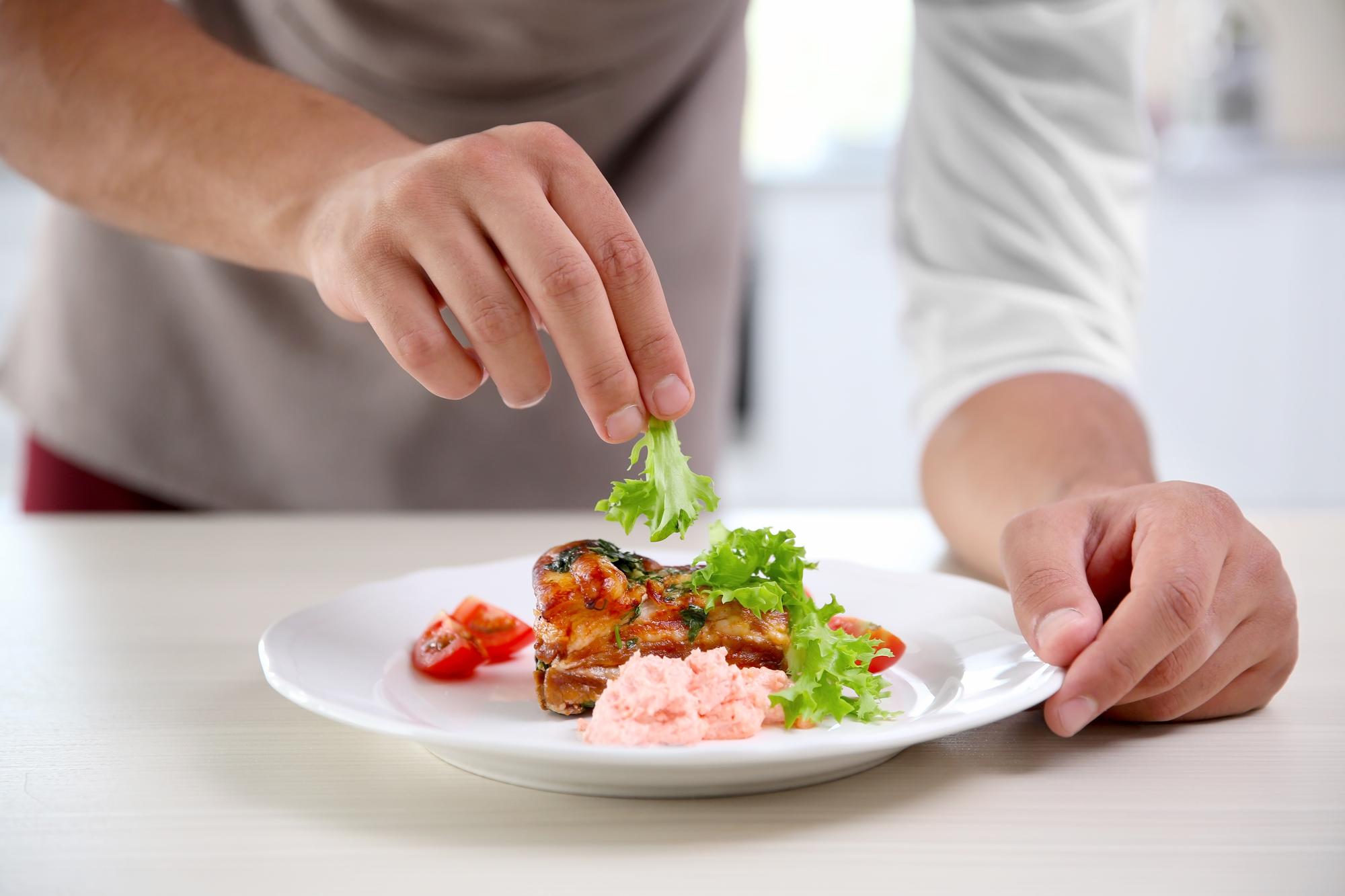 chef quickly plating a modern dish in a bright kitchen